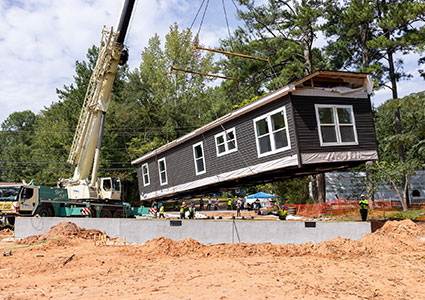 Manufactured home being lowered into place by a crane