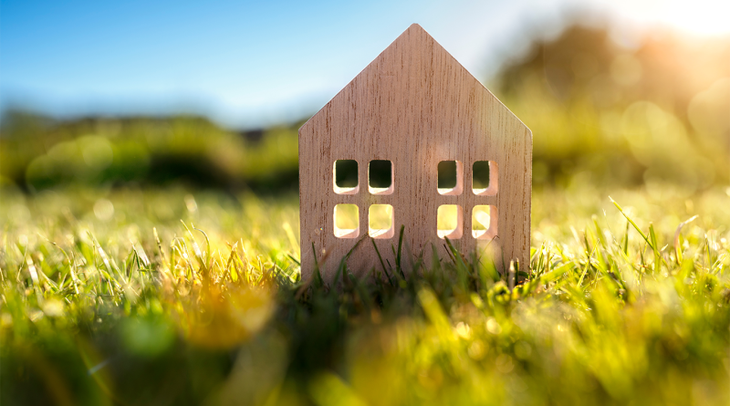 Wooden home model in meadow to support eco-luxury article