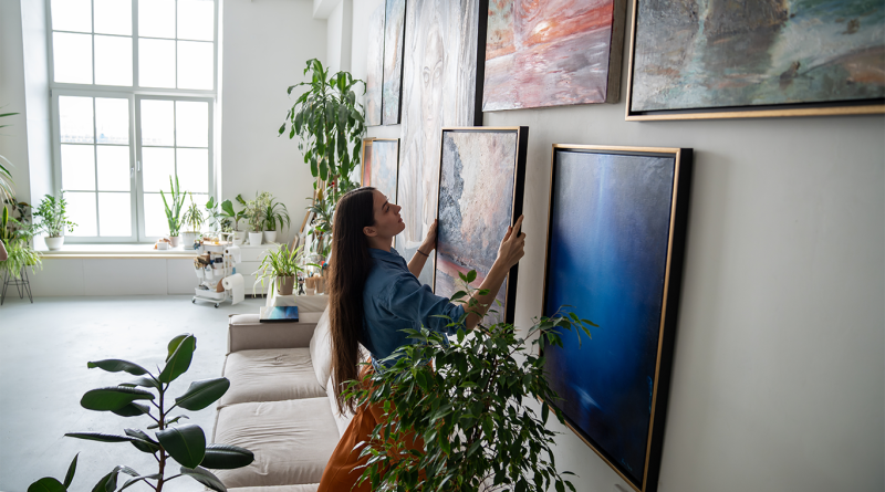 Woman hanging art in home to support Blue-chip art article