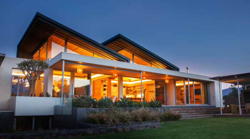 You Can Stay in These 7 Amazing Celebrity Homes Modern luxury home with large glass windows and warm interior lighting, available as a celebrity home vacation rental.