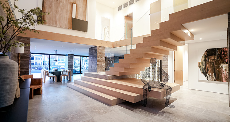 Inside the rise of Burkhart Brothers Construction a modern and spacious interior, featuring a prominent, light-colored wooden floating staircase with glass railings