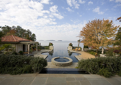 a luxurious lakeside property featuring a large pool area with a built-in spa