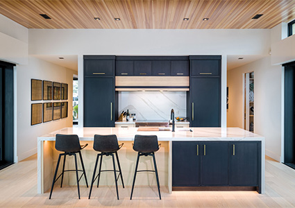 a modern kitchen design featuring a large island with seating and dark cabinetry