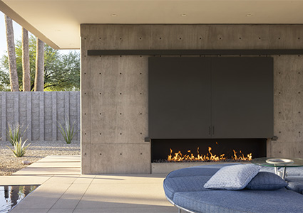 an outdoor living area of a modern residence, featuring a built-in fireplace and minimalist design elements
