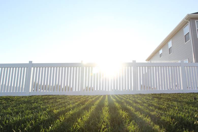 White fence in garden on sunny day by Cedar Mountain Fence Company
