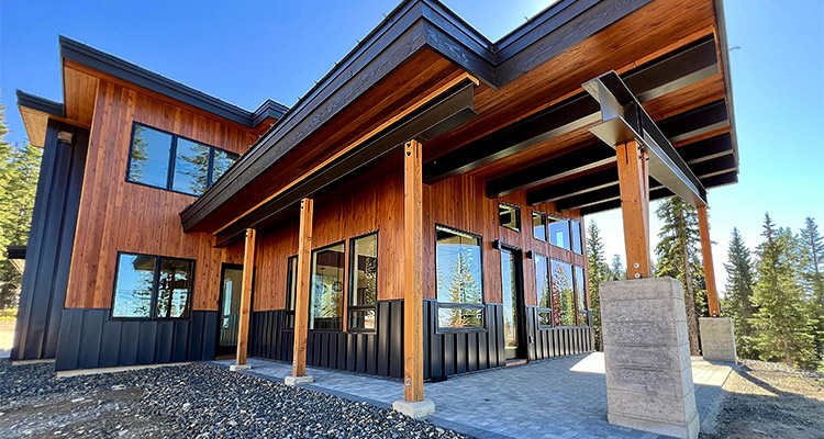 a modern timber frame home featuring a mix of wood siding and dark metal cladding
