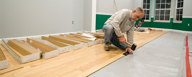 Man laying underlay in home by floorMuffler®