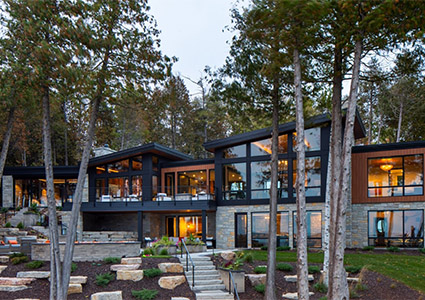 a modern multi-level home nestled in a wooded, hilly landscape