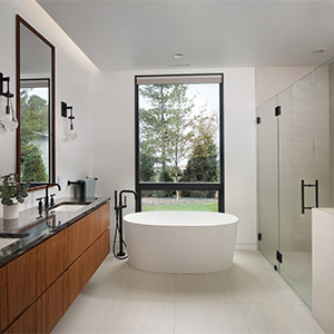  a modern bathroom interior featuring a freestanding tub positioned in front of a large window, a dark wood vanity with a black countertop, and a walk-in glass shower. 