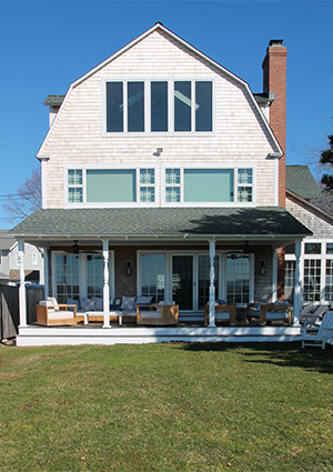 a multi-story residential building with a gambrel roof and a large covered porch