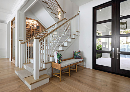 a contemporary entryway showcasing a custom black-framed metal and glass front door paired with a staircase featuring white spindles and wooden treads. 