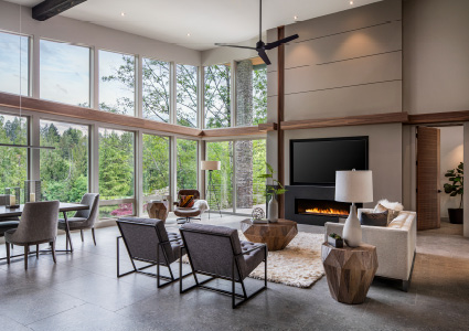 a contemporary living room features floor-to-ceiling windows with a scenic wooded view