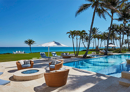 the pool area of a luxurious oceanfront mansion