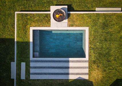 a modern, rectangular outdoor concrete plunge swimming pool set within a grass lawn.