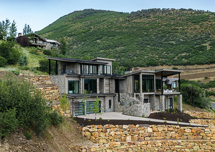 a modern, multi-story home built into a steep hillside in a mountainous region