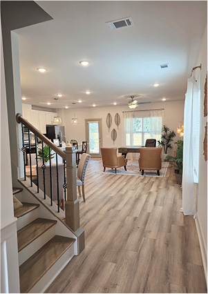 a modern open-concept interior featuring light wood flooring, a staircase with dark metal railings, and recessed lighting