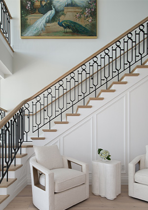 an elegant interior staircase featuring a wrought iron balustrade with a wooden handrail