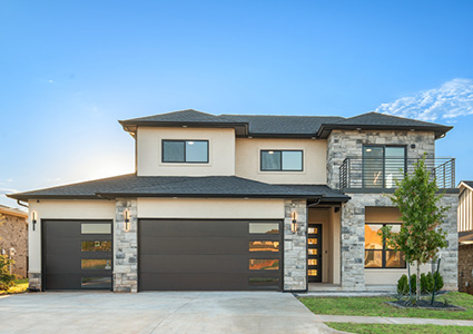 a contemporary two-story home is a model plan featuring a stone and stucco exterior