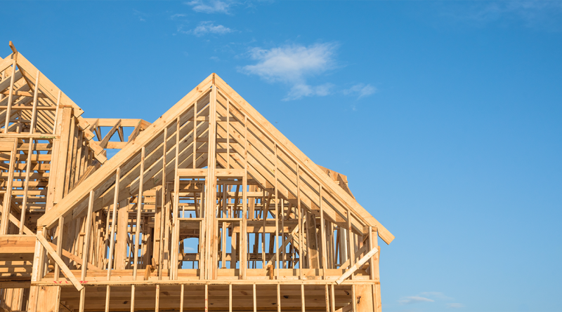 Wood-framed residential homes under construction against a clear blue sky in Florida residential development project