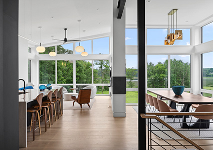 a modern open-plan living space with vaulted ceilings, large windows, and a combination of kitchen, dining, and seating areas