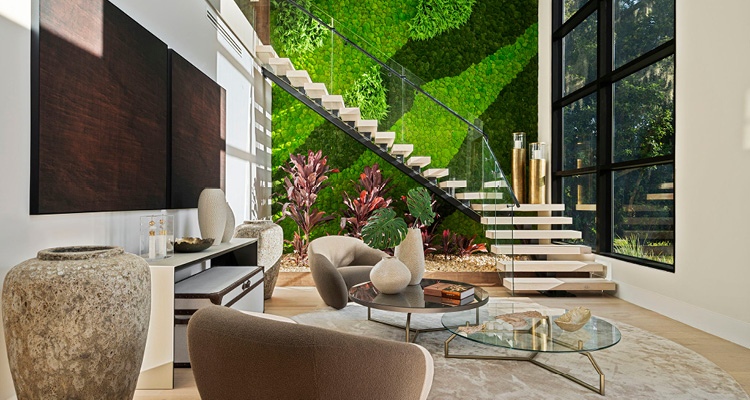 a modern indoor residential staircase featuring a floating design, glass railing, and a large moss wall background