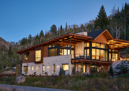 a modern, multi-level mountain residence at twilight, nestled into a wooded hillside