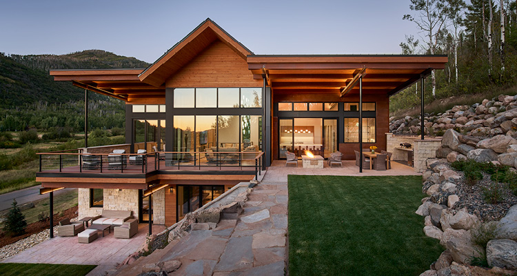 a luxury multi-level Mountain Contemporary home nestled into a sloping hillside at dusk.