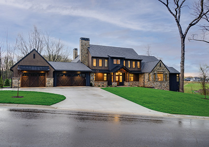 a large, two-story modern farmhouse style home. The architecture combines rustic textures with clean, contemporary lines