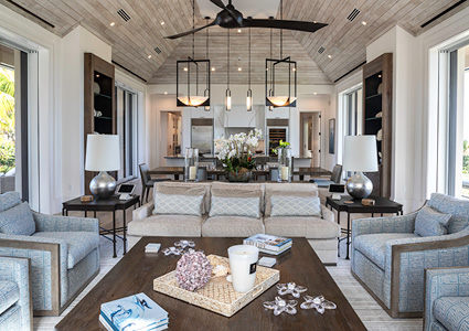 a luxury, open-concept coastal living room featuring a symmetric furniture layout, a prominent whitewashed wood-plank ceiling, and large lantern pendant lights hanging above the central space