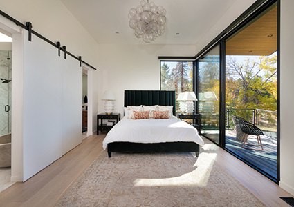 A contemporary bedroom featuring a sleek black upholstered bed and large floor-to-ceiling windows