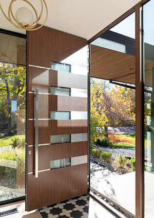 a modern architectural pivot front door crafted from wood panels alternating with frosted glass sections