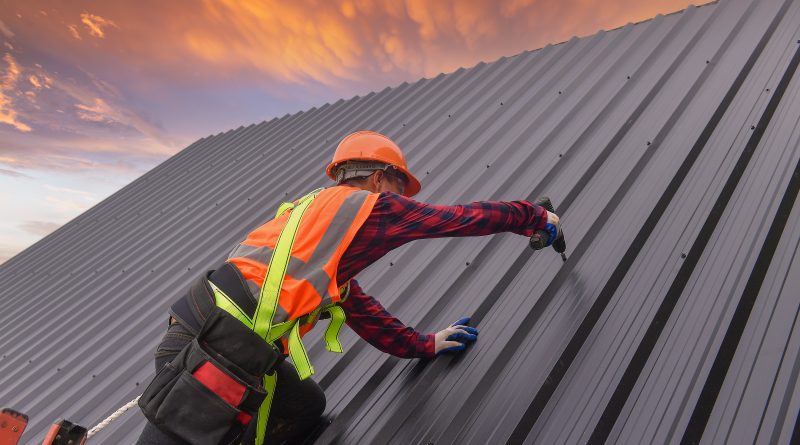 roofing construction worker adding metal roofing to home