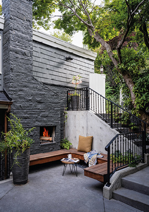 a cozy, modern outdoor patio nestled against a stone wall and an exterior staircase.