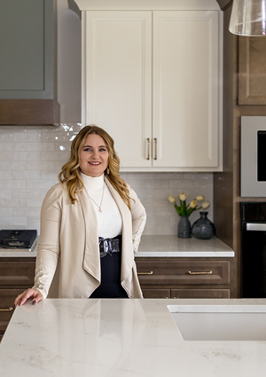 a person in a modern kitchen with cream-colored cabinetry and a white countertop