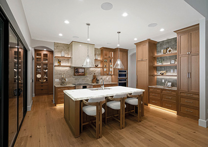 a spacious, upscale modern kitchen featuring natural wood cabinetry, stone textures, and warm, integrated lighting