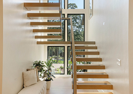 a bright, modern interior hallway dominated by a central, minimalist staircase.