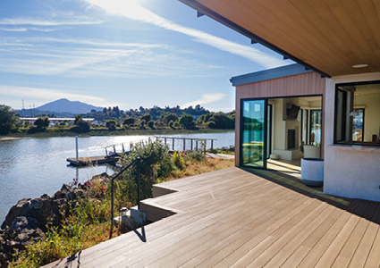 a modern waterfront home with a large wooden deck