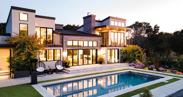 a luxurious, multi-level modern house at twilight, featuring an integrated backyard swimming pool