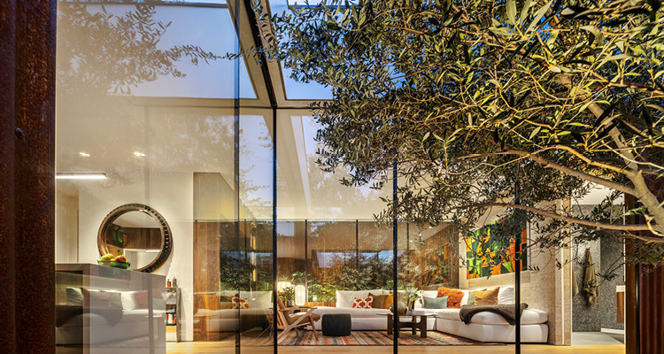 a modern, luxury home at dusk or dawn, viewed from the outside through large glass walls