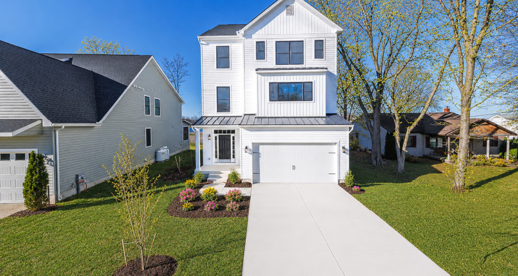 a modern, three-story white house with a bright, sunny yard