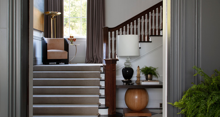 the interior of an elegant, multi-level home entryway or hallway, viewed through a framed doorway