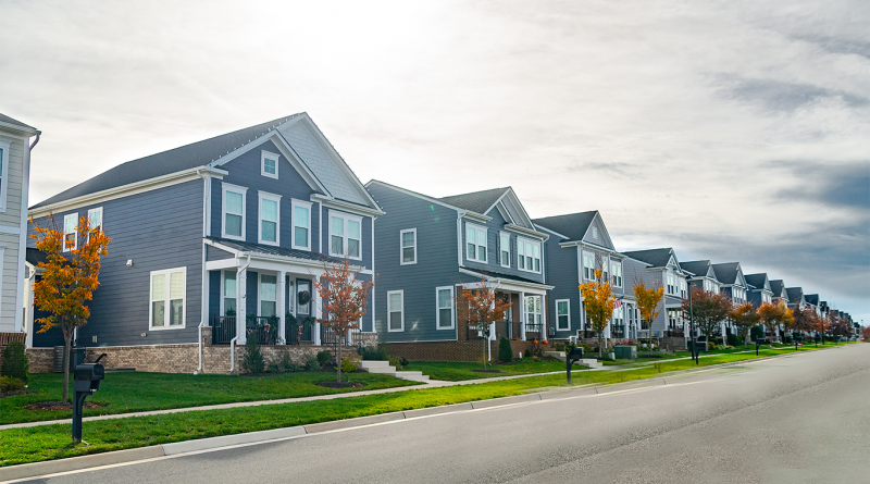 Neighborhood of detached houses by the roadway. Summer day