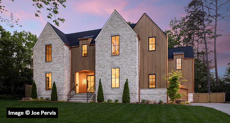 a large, modern two-story luxury home at dusk under a purple and pink sky