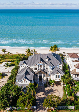 an aerial photograph of a large, luxurious multi-story beachfront estate situated directly along a coastline