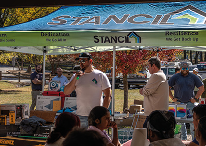 an outdoor event taking place under a blue and white canopy tent