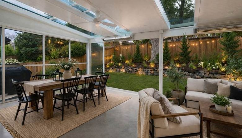 Interior view of a solid-roof patio cover with integrated recessed lighting and open-beam design. The white aluminum structure includes skylights for natural light and supports a ceiling fan for air circulation.