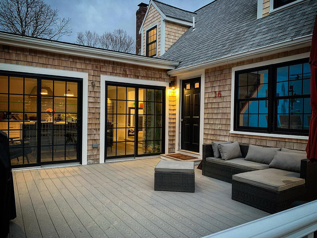 Multiple large-format black-framed windows and gliding doors by Asher connect interior spaces with outdoor living areas.
