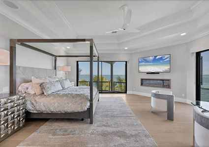 a modern dark wood four-poster canopy bed paired with a neutral patterned duvet.
