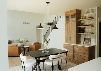 an open-plan dining and living area featuring a dark wooden dining table with white upholstered chairs