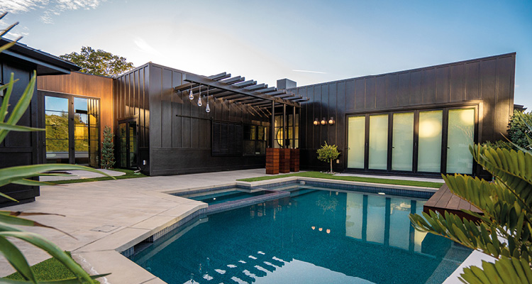 With a people-first approach to building, Burkhart Brothers Construction continues its rise as one of Newport Beach’s leading luxury home builders a modern backyard patio with a swimming pool and dark metal siding